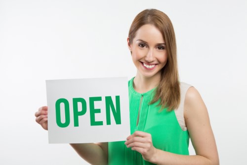 woman in green dress holding open sign to keep messages up to date